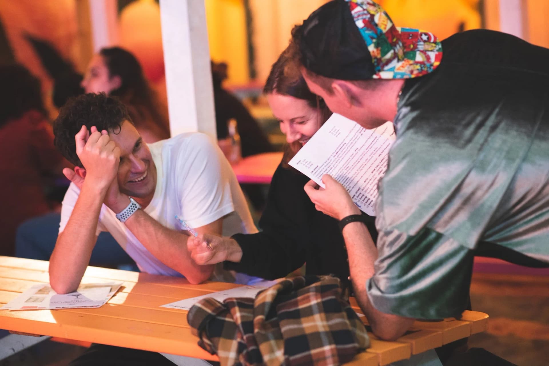 Three players huddled over a quiz answer sheet at a Get Social night