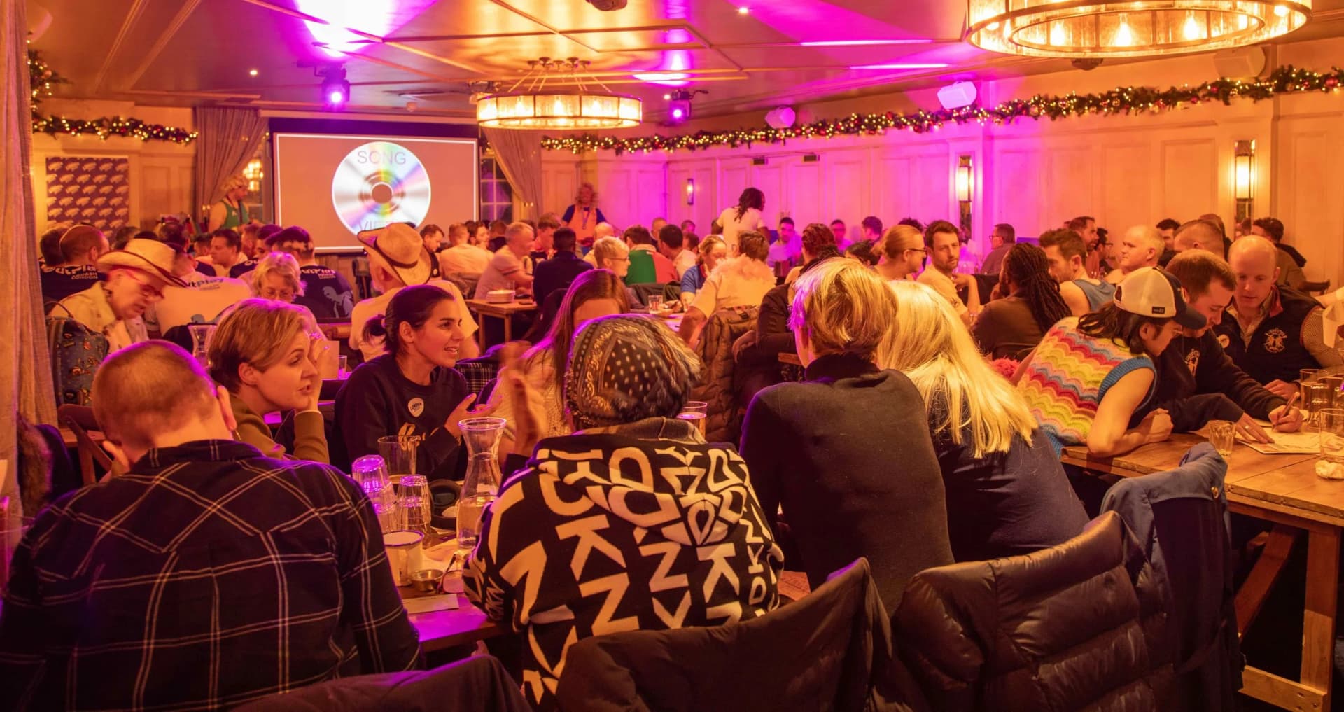 A packed Social Quiz Club night, teams laughing over their answer sheets